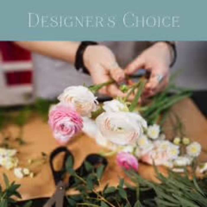 Hands arranging pink and white ranunculus flowers on a table