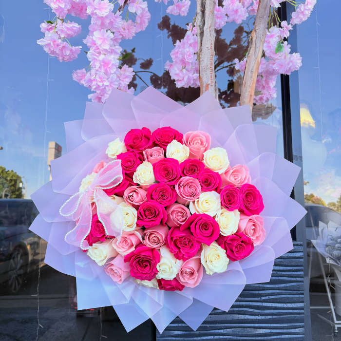 Large bouquet of pink and white roses wrapped in lavender paper
