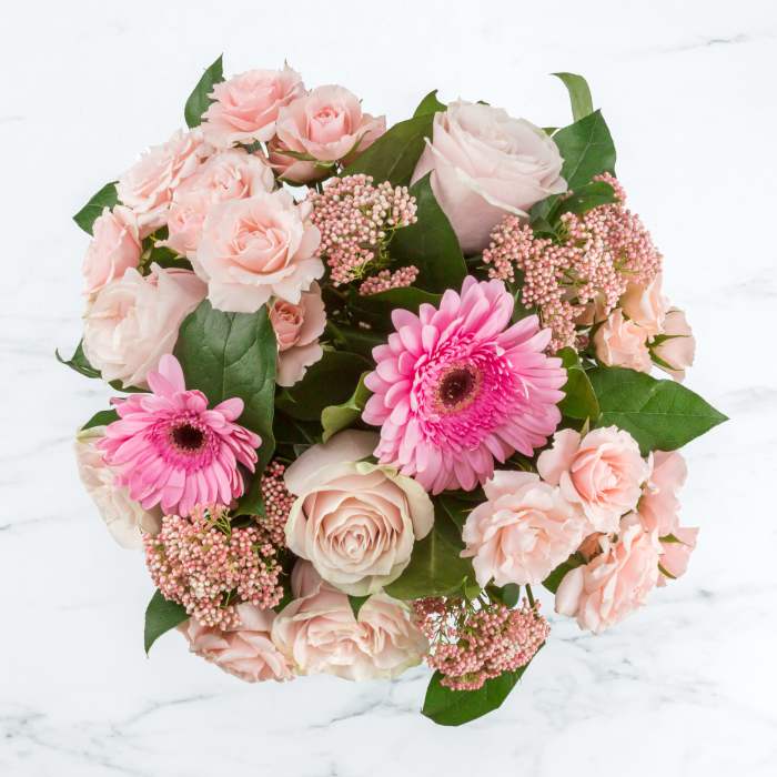 Pink roses and gerbera daisies arranged in a round bouquet