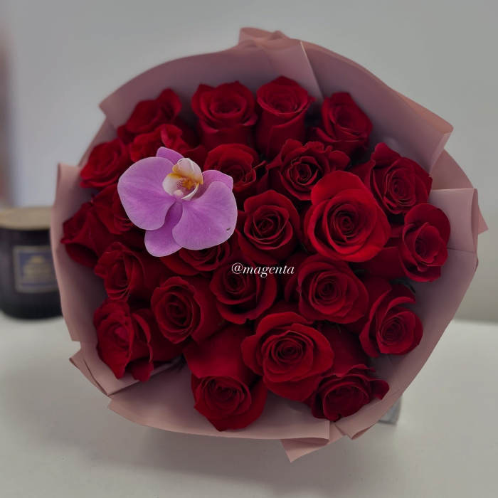 Bouquet of red roses with a single lavender orchid in pink wrap