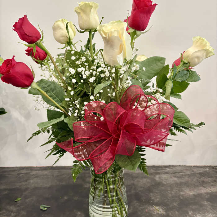 Red and white roses in a glass vase with a large red ribbon