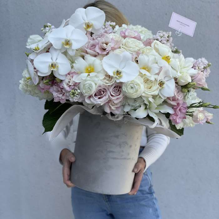 Large pastel bouquet with white orchids and pale roses in a gray hatbox