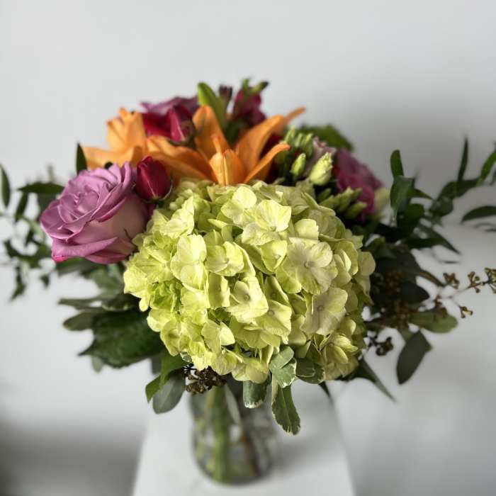 Bouquet of hydrangeas, roses, and lilies in a glass vase