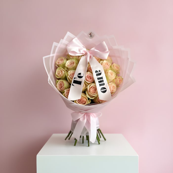 Bouquet of pale pink roses wrapped in pink paper with a satin bow