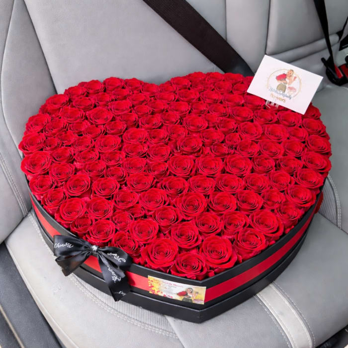 Heart-shaped box filled with red roses and tied with a black ribbon