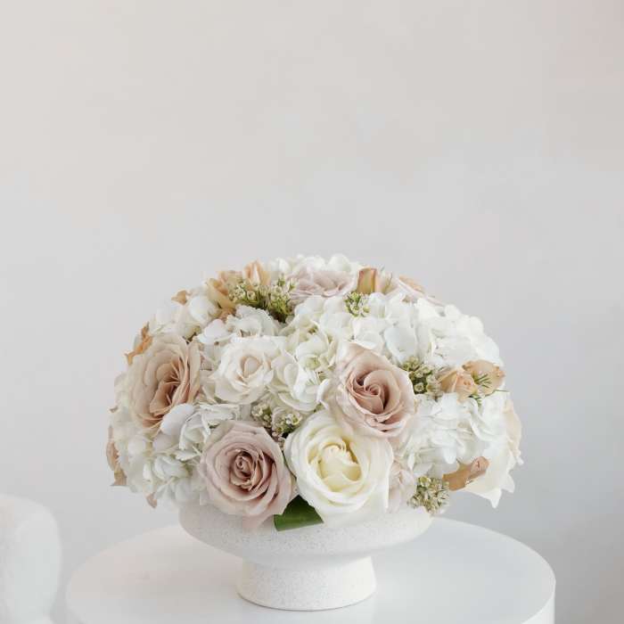 Blush and white roses with white hydrangeas in a white pedestal vase
