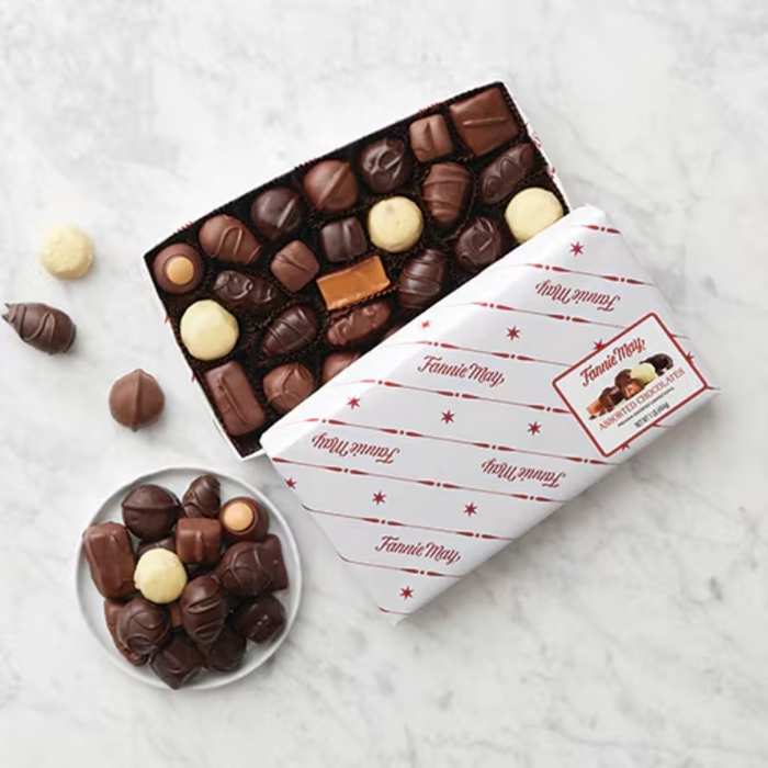 Box of assorted chocolates with a few pieces scattered beside it