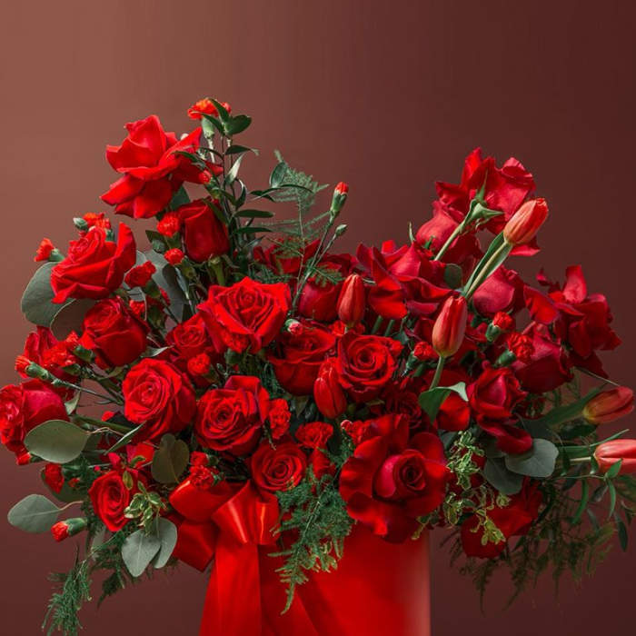 Red rose arrangement in a red hatbox with ribbon