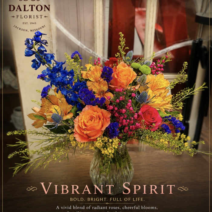 Bright mixed bouquet in a clear glass vase with orange, blue, and pink flowers