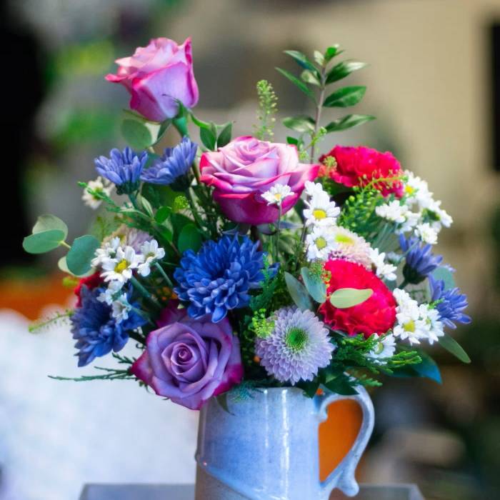 Mixed bouquet of roses and daisies in a blue ceramic mug