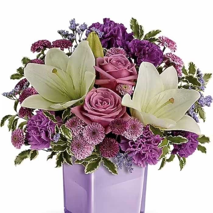 Purple and white flower arrangement in a lavender glass vase