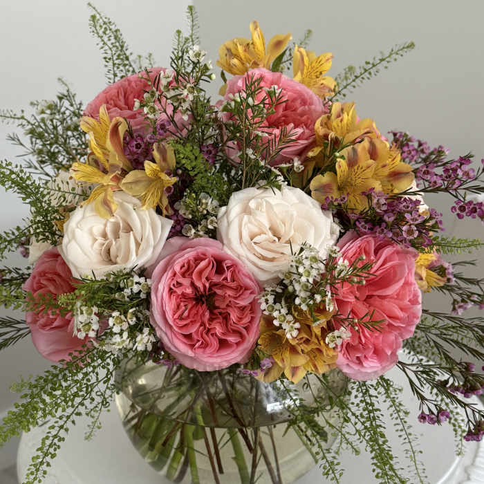 Pink and white roses with yellow flowers in a glass vase