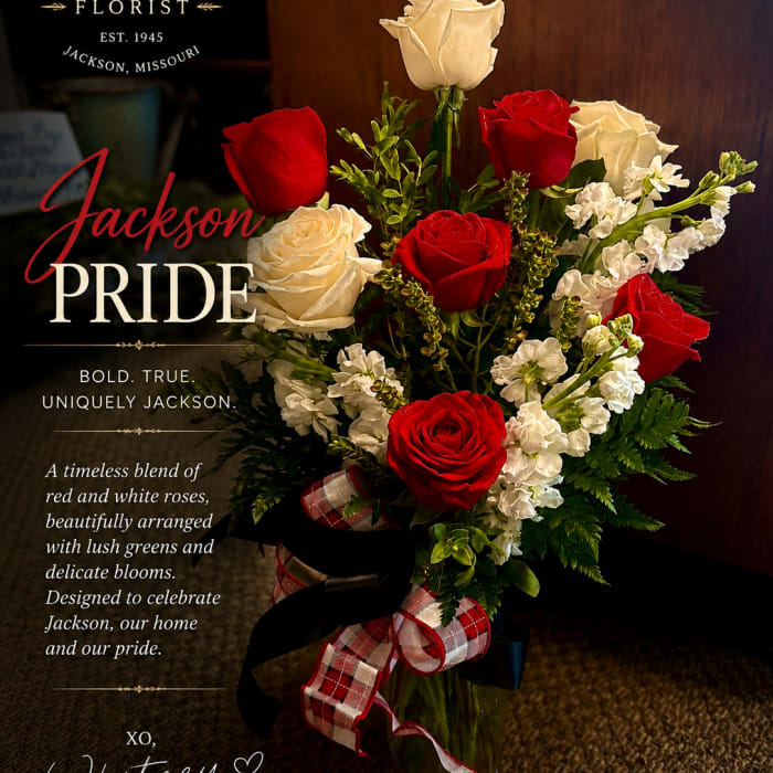 Red and white roses arranged in a glass vase with a plaid ribbon