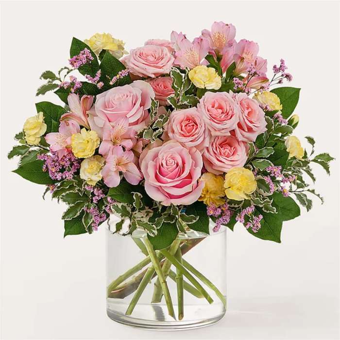 Pink roses and yellow carnations in a clear glass vase