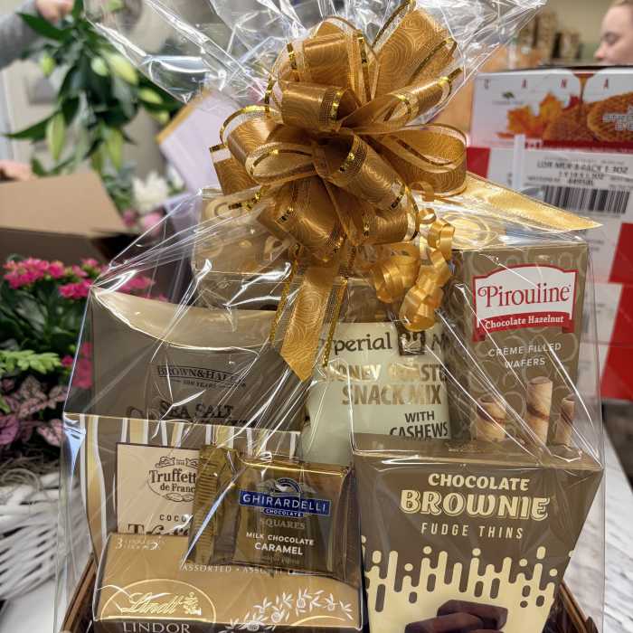 Gift basket of assorted chocolates and snack mixes wrapped with a gold bow