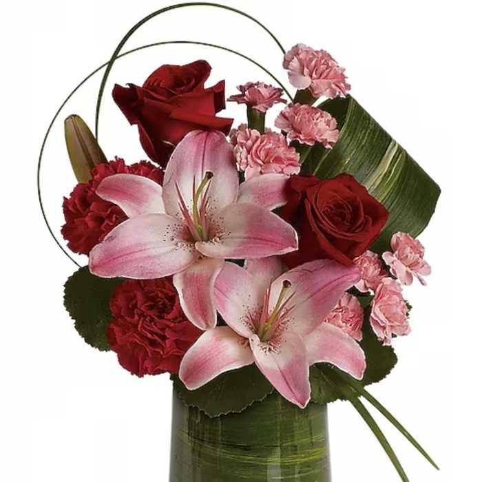Pink lilies and red roses arranged in a green glass vase