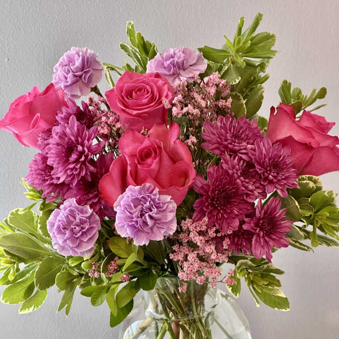 Pink roses and purple flowers in a clear glass vase