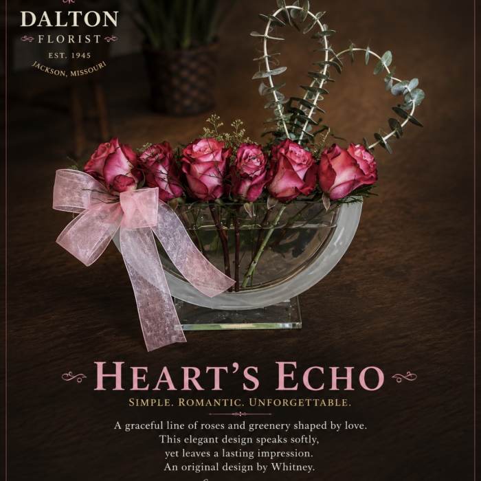 Pink roses in a clear bowl vase with a pink ribbon and heart-shaped eucalyptus