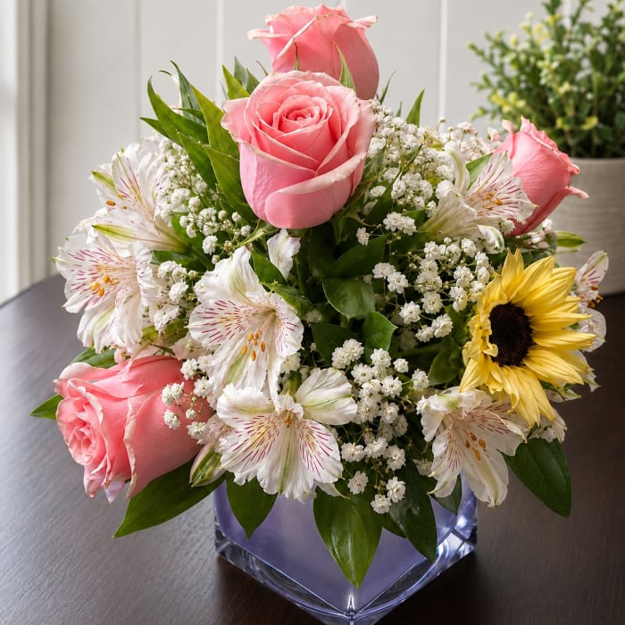 Pink roses and white alstroemeria in a square glass vase
