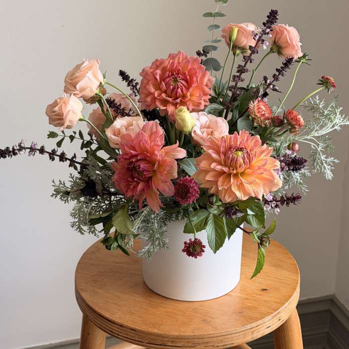 Peach and coral flower arrangement in a white vase