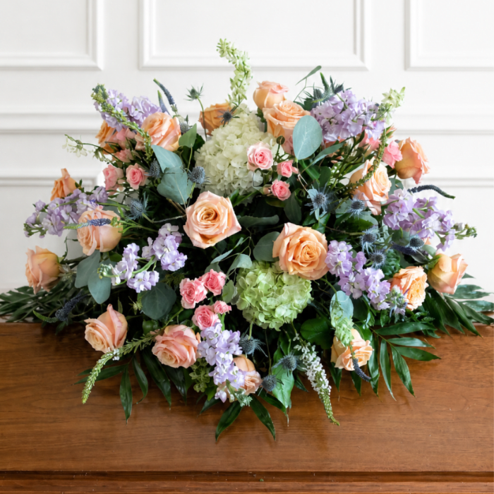 Large pastel floral arrangement with peach roses, lavender blooms, and green hydrangeas