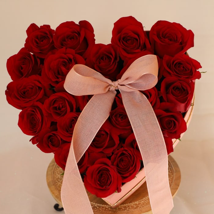 Heart-shaped box of red roses with a pink ribbon bow
