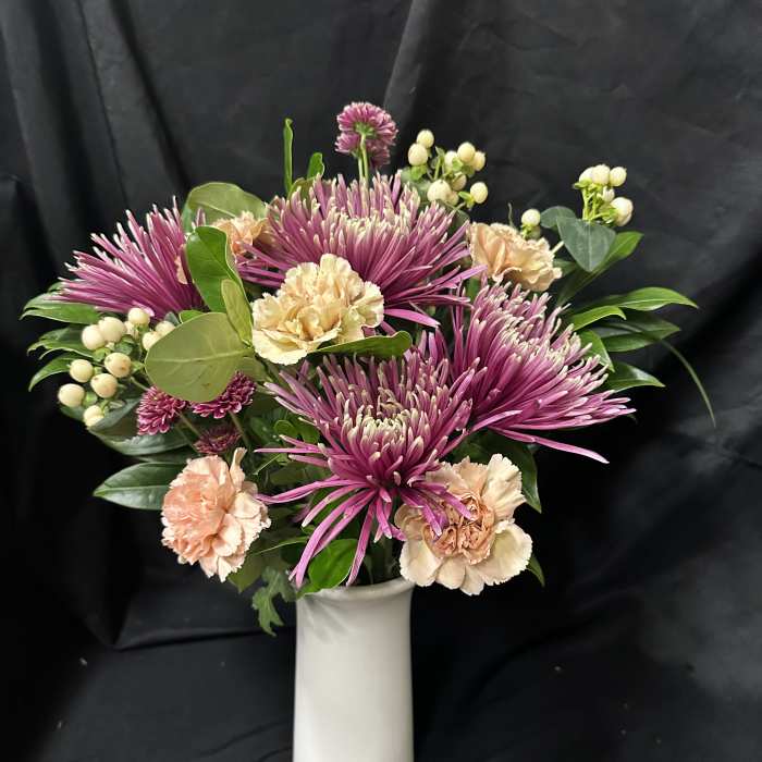 Pink chrysanthemums and peach carnations in a white vase