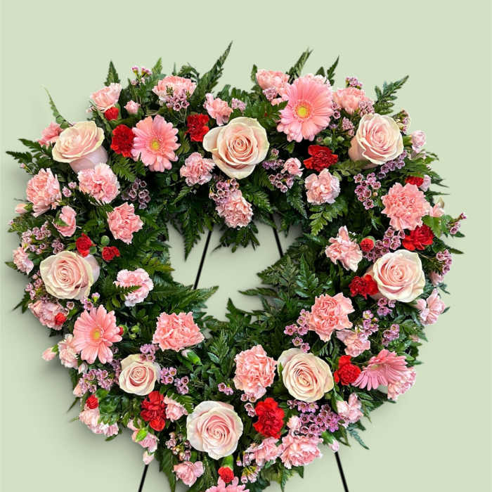 Heart-shaped floral wreath with pink roses, carnations, and daisies