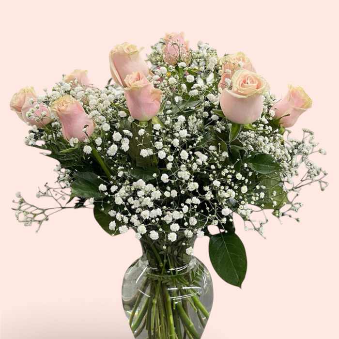 Pink roses and baby's breath arranged in a clear glass vase