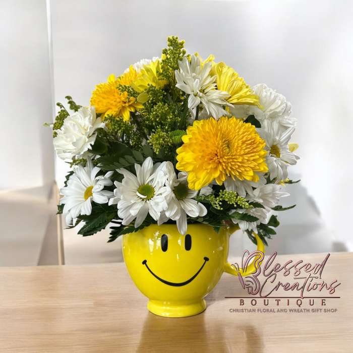 Yellow smiley-face mug holding white and yellow flowers