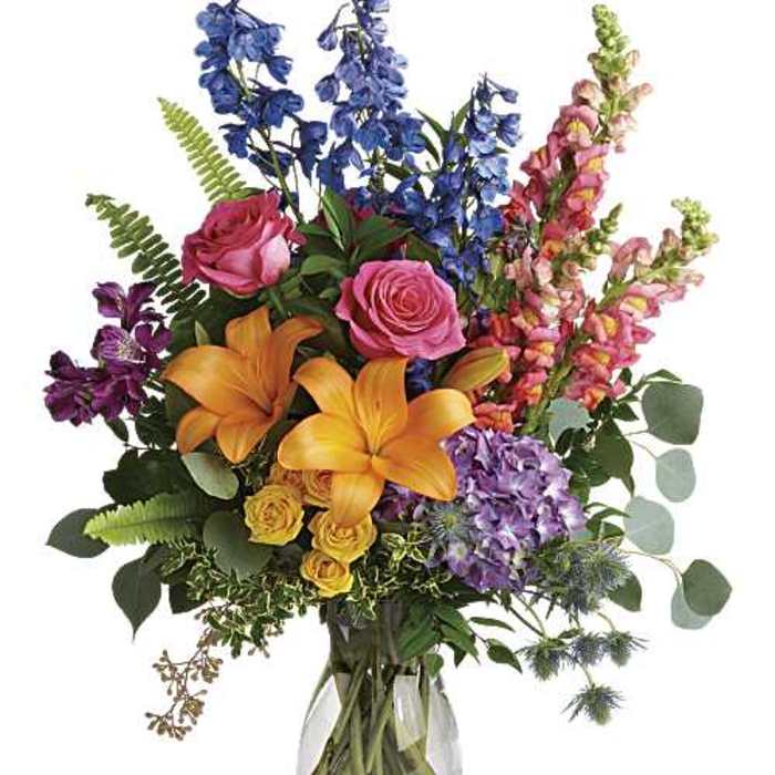 Colorful bouquet of roses, lilies, and snapdragons in a clear glass vase