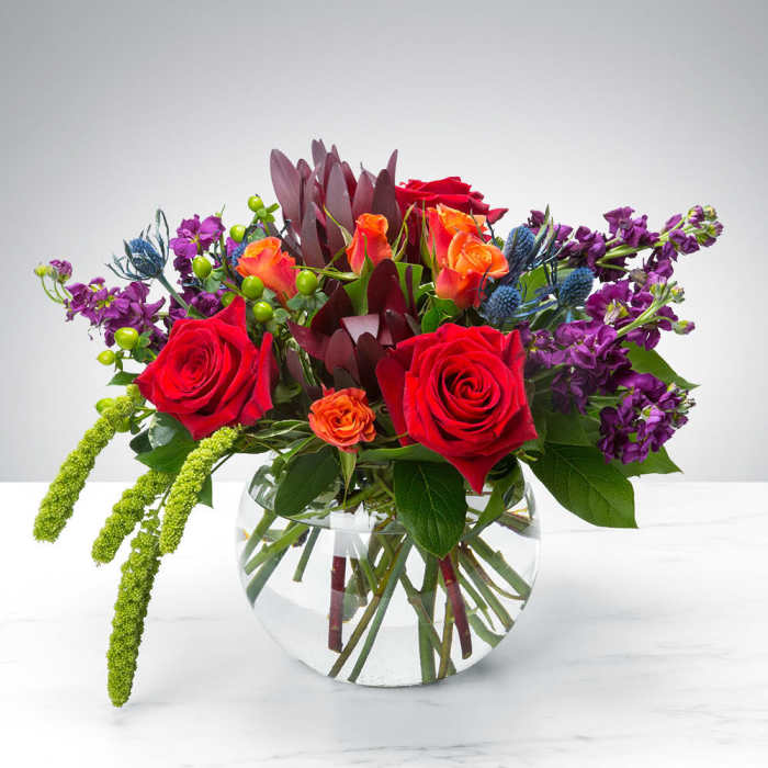 Mixed bouquet of red and orange roses in a clear glass vase