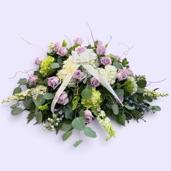 Lavender roses and white hydrangeas in a low floral arrangement with a ribbon bow