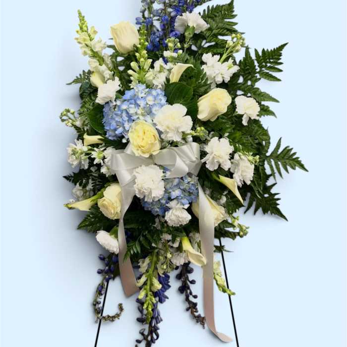 Standing floral spray with white roses, blue hydrangea, and ribbon