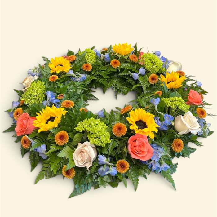Oval floral wreath with sunflowers, roses, and blue flowers