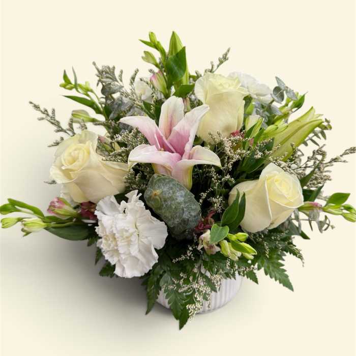 Bouquet of white roses, pink lilies, and white carnations in a vase