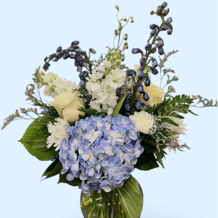 Blue hydrangea bouquet with white flowers in a clear glass vase