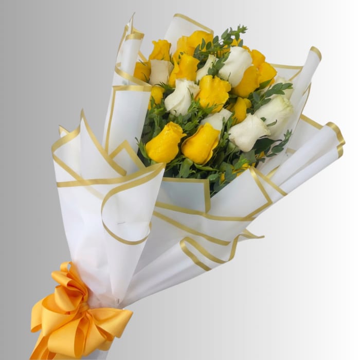 Bouquet of yellow and white roses wrapped in white paper with gold trim