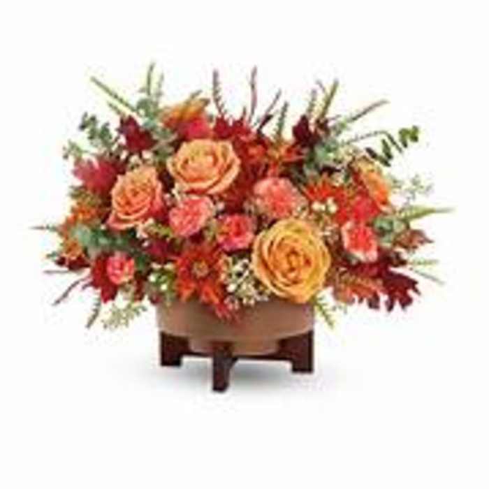 Orange and red floral arrangement in a low wooden container