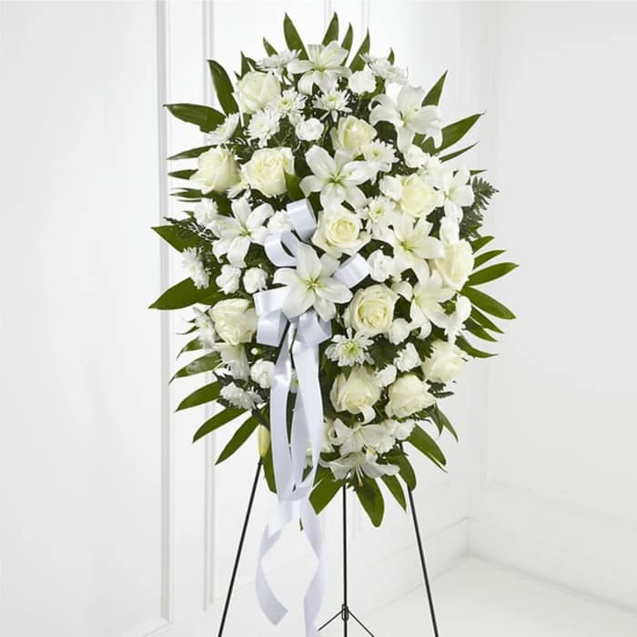 White floral standing spray with roses and lilies on an easel