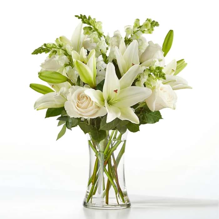 White lilies and roses in a clear glass vase