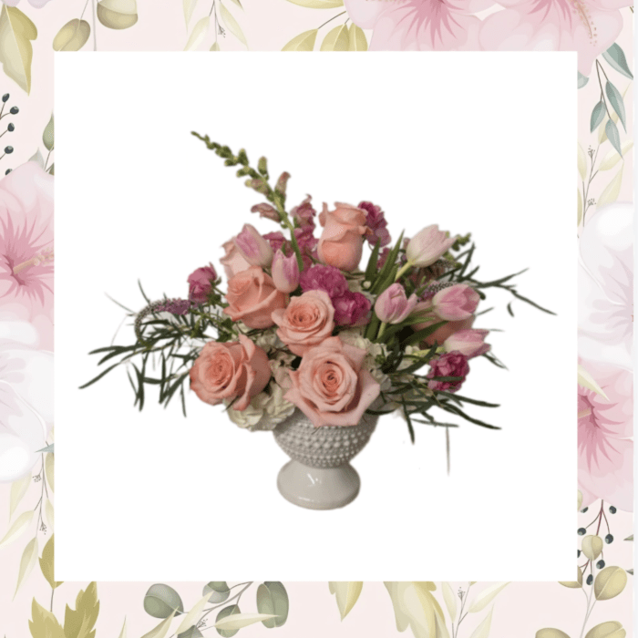 Pink roses and tulips arranged in a white pedestal vase