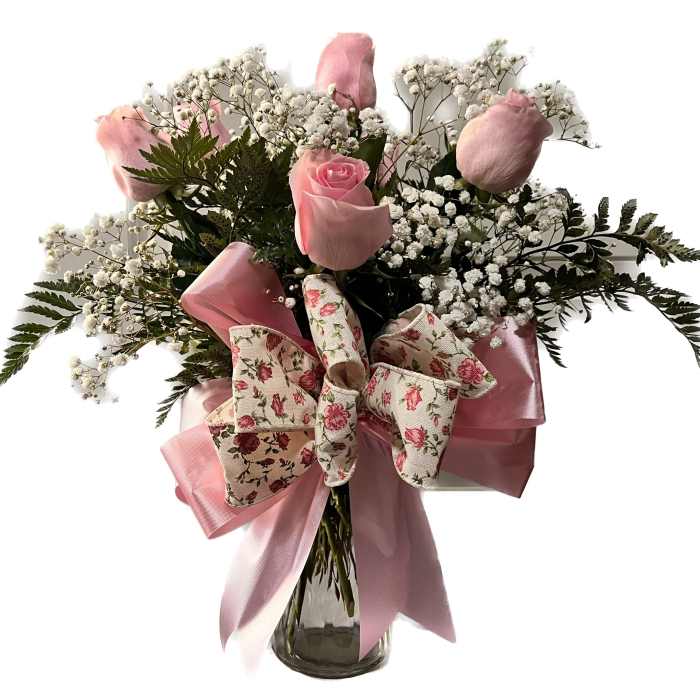 Pink roses in a glass vase with baby's breath and a floral bow