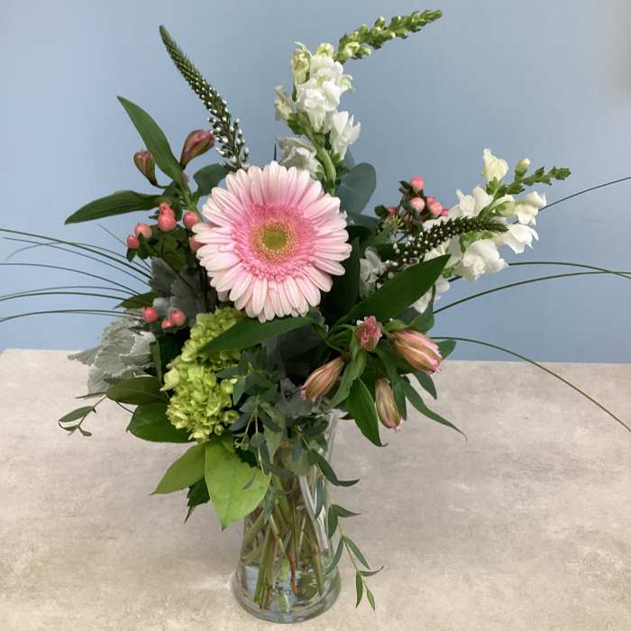 Pink gerbera daisy arrangement in a clear glass vase with white blooms