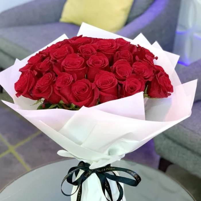 Bouquet of red roses wrapped in white paper with a black ribbon