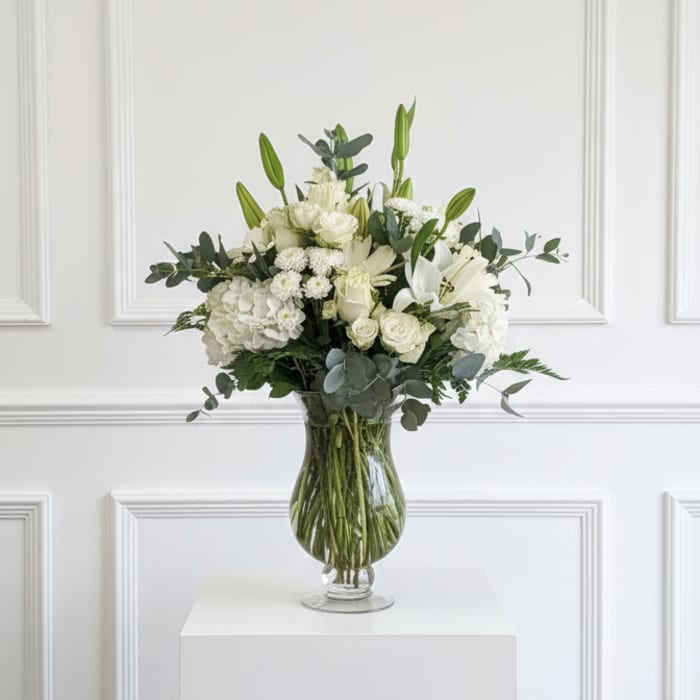 White floral arrangement in a clear glass vase on a pedestal