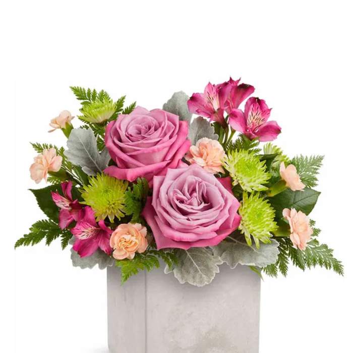 Pink roses and mixed blooms in a square gray vase