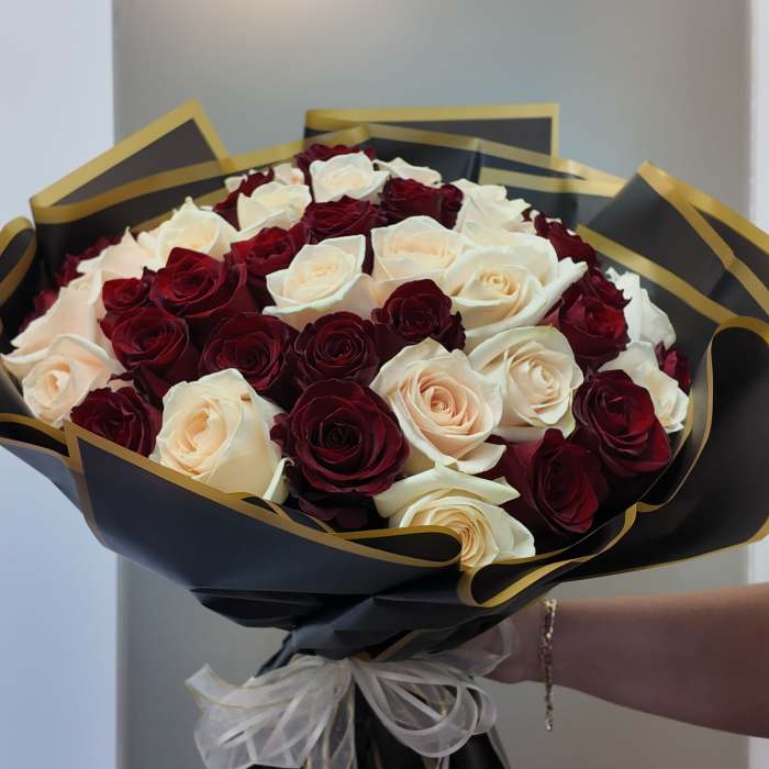 Bouquet of red and white roses wrapped in black paper with gold trim