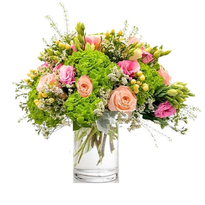 Bouquet of pink and peach roses with green hydrangeas in a clear glass vase