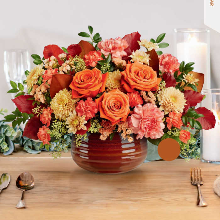 Orange and pink floral arrangement in a round vase on a table